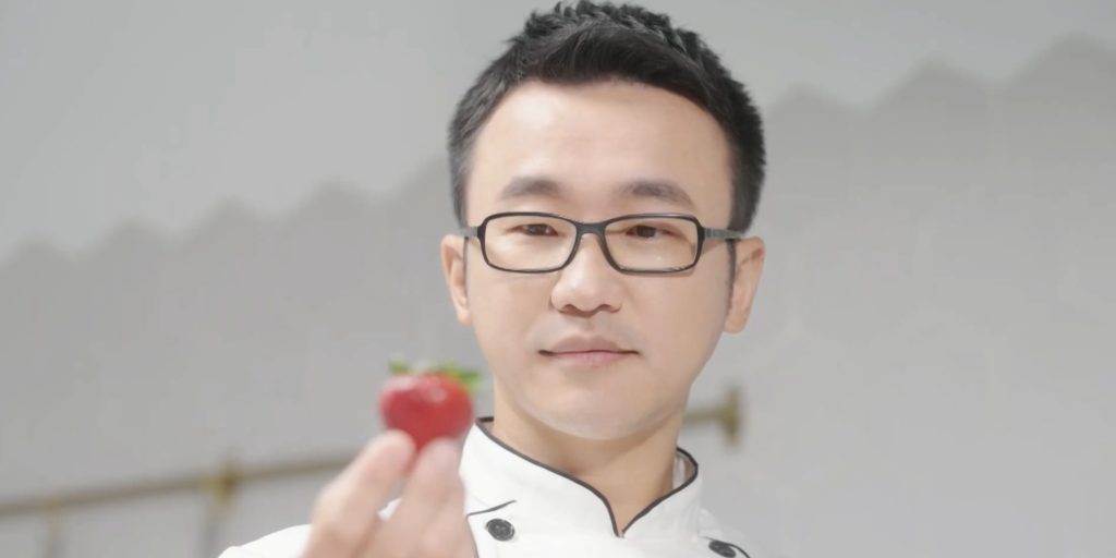 甜一口糖葫蘆｜品牌主吳章榮手持單顆草莓特寫肖像，白色主廚服質感畫面