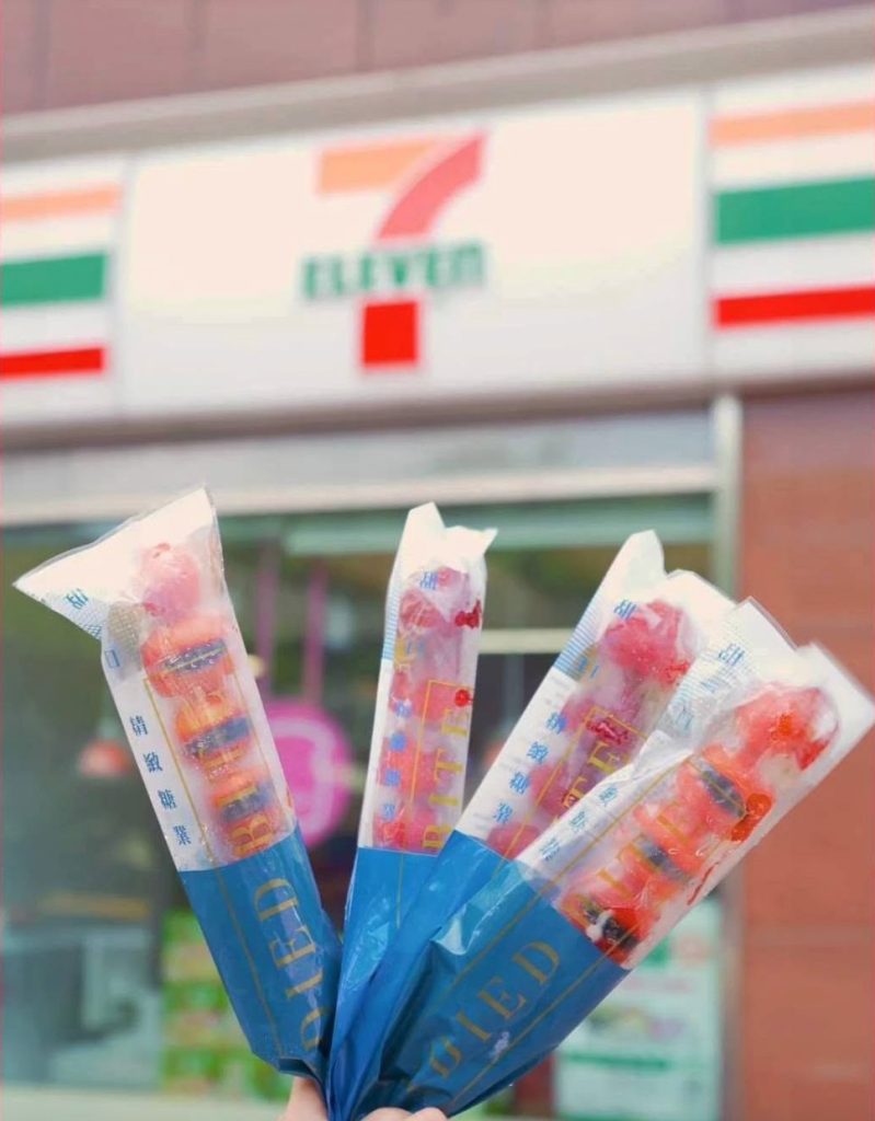 甜一口糖葫蘆｜手持五支包裝糖葫蘆於7－ELEVEN門市招牌前展示